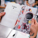 The Cake Book by Crumbs & Doilies open to a recipe page with berries and fruit compote ingredients.